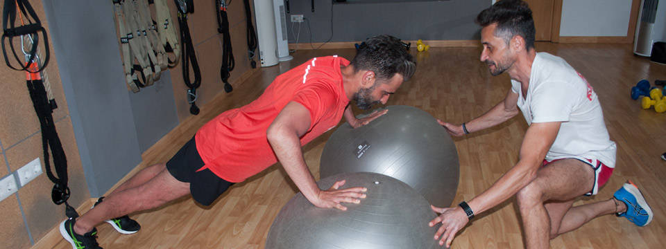 Entrenador Personal en el centro de Badajoz, Héctor Gil, entrenamiento en sala guiando y corrigiendo posturas con pelotas de pilates.
